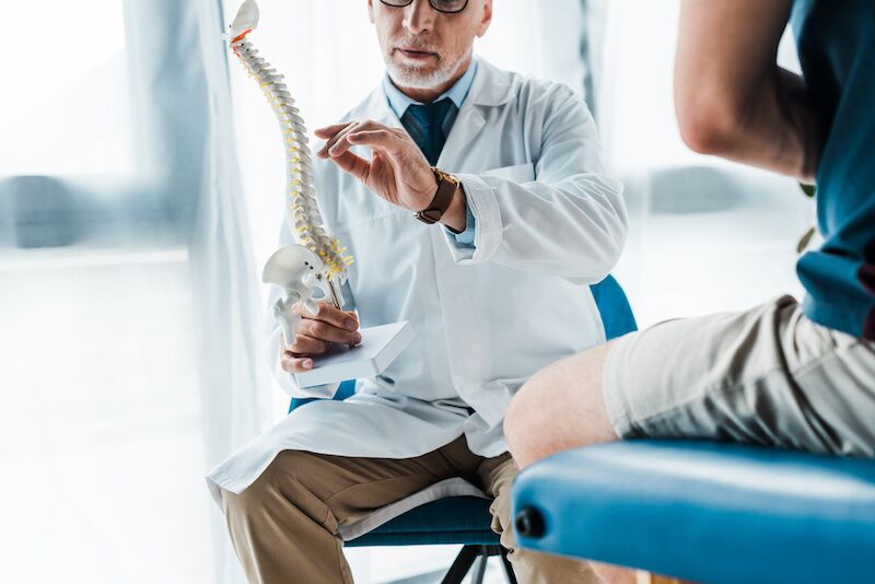 doctor showing patient model of spine
