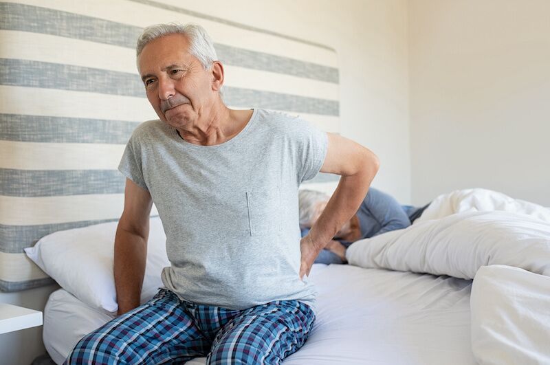 man getting out of bed with back pain