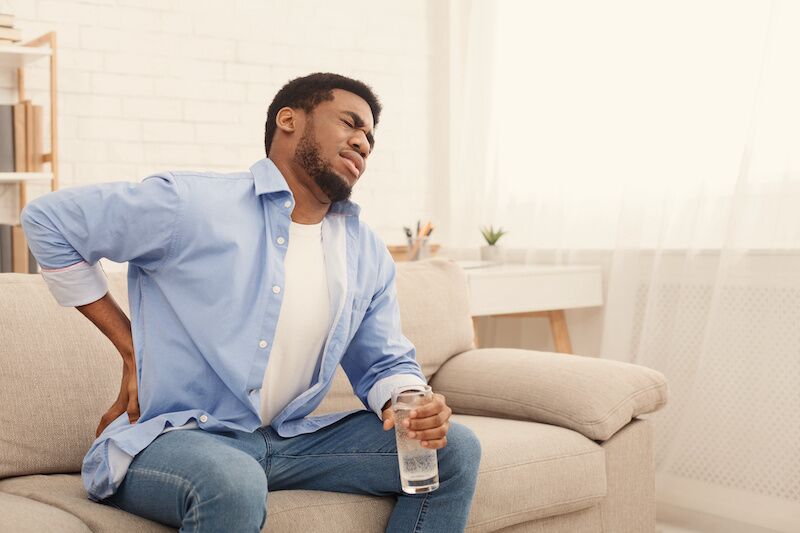 man sitting on couch with back pain